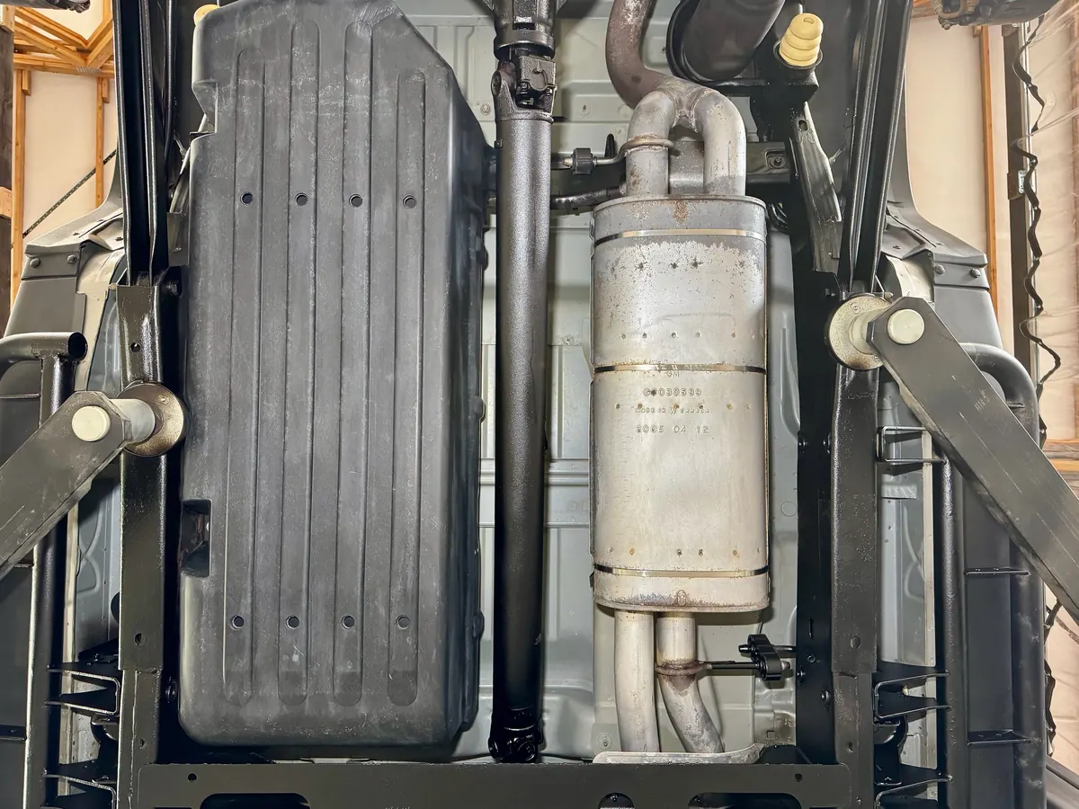 The same frame rails alongside the fuel tank and muffler after dry ice cleaning and undercoating