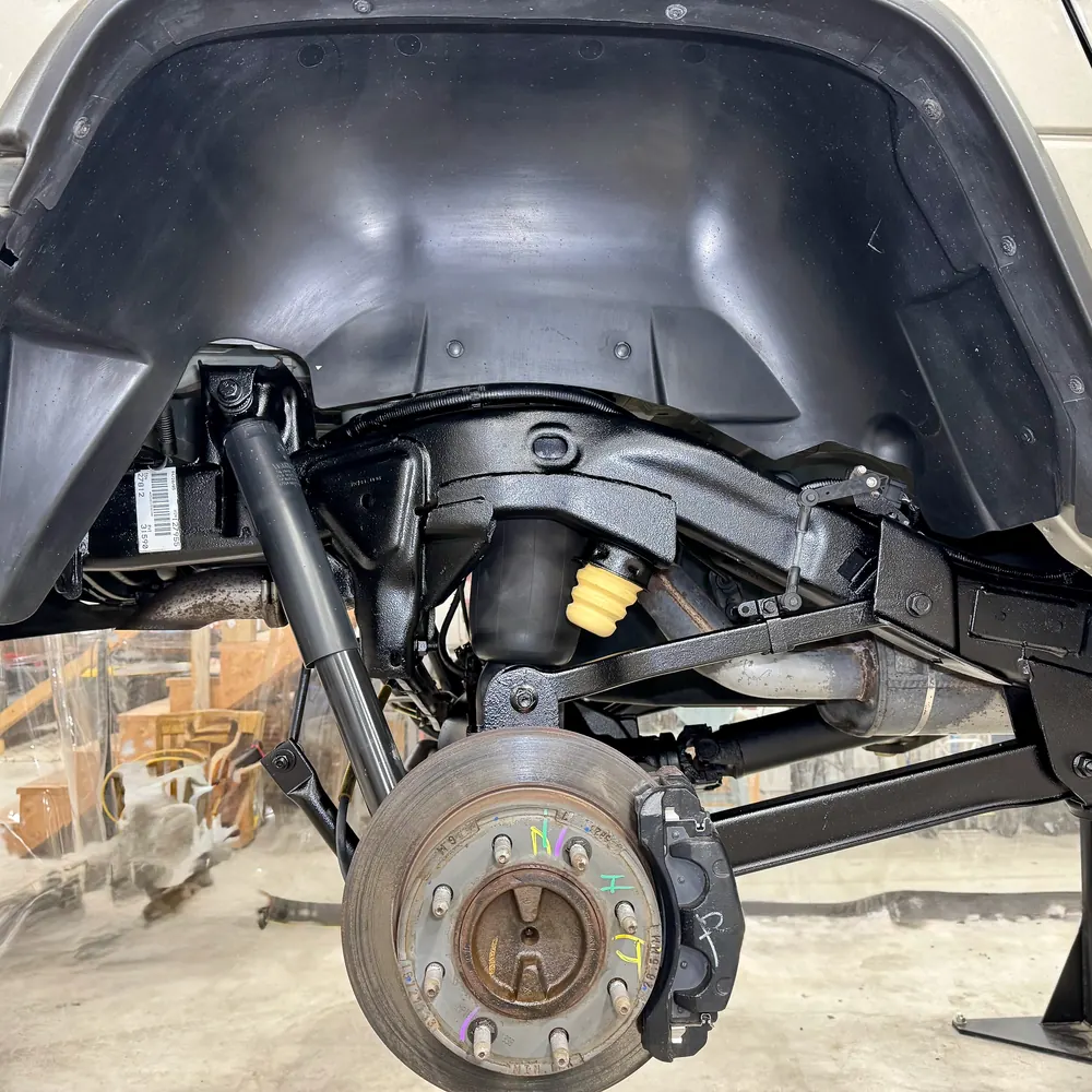 The same rear wheel well after undercoating, frame rail and suspension sealed in black DINITROL 4941